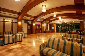 Un hall d’entrée spacieux, avec des canapés à rayures, un plancher en bois et un lustre.