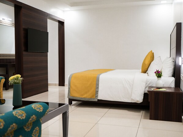 Una habitación de hotel con cama, televisor, escritorio y silla.