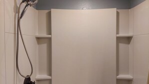 Een douche met een handdouche en een kraan aan de muur.