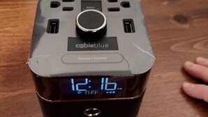 Een draagbaar apparaat met een digitaal scherm op een houten ondergrond.