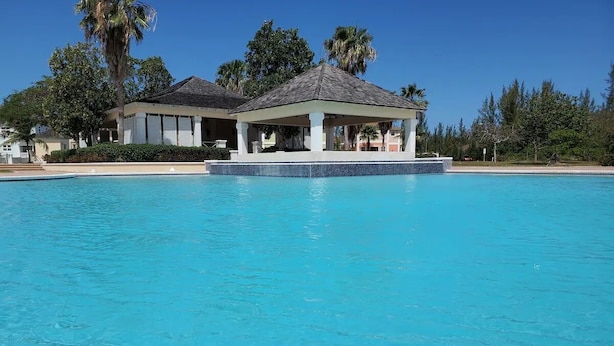 En stor swimmingpool med et overdækket pavillon i baggrunden.