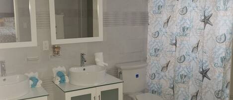 A bathroom with a white sink, two mirrors, a toilet, and a shower curtain with a sea-themed pattern.