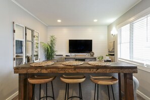 A kitchen with a wooden island, three bar stools, a flat-screen TV, and a window with blinds. - Lighthouse 5 (Kimberling City)