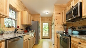 A wooden cabin-style kitchen with a refrigerator, microwave, stove, and granite countertops. - “Just BEE🐝Log Cabin"-Stunning, peaceful, NEW, -10 min to Dwtn Asheville, dogs ok (Asheville)