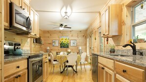 A wooden interior with a kitchen, dining area, and ceiling fan. - “Just BEE🐝Log Cabin"-Stunning, peaceful, NEW, -10 min to Dwtn Asheville, dogs ok (Asheville)