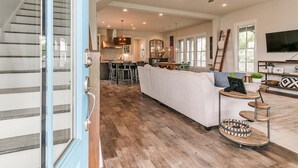 A spacious living area with a large sofa, a dining table, and a kitchen in the background.