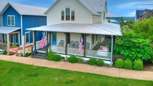 A two-story house with a porch, American flags, and a well-maintained lawn.