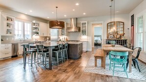 A spacious kitchen with a central island, bar stools, and a dining area with a wooden table and chairs.