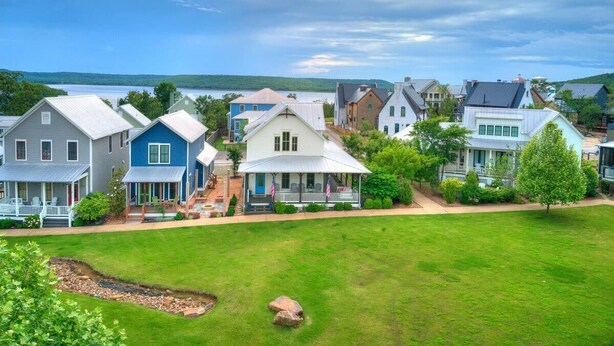 A residential area with houses, a grassy lawn, and a body of water in the background.