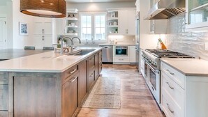 A modern kitchen with a central island, stainless steel appliances, and a hanging light fixture.