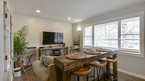 A modern kitchen with a wooden bar, bar stools, a television, and a large window with blinds. - Lighthouse 5-5B (Kimberling City)