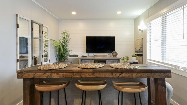 A kitchen with a wooden island, three bar stools, a flat-screen TV, and a window with blinds. - Lighthouse 5-5B (Kimberling City)