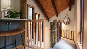 A kitchen with a bar stool, wooden beams, and a view of the outdoors.