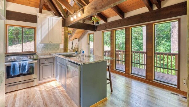 A spacious kitchen with wooden beams, large windows, and a central island.