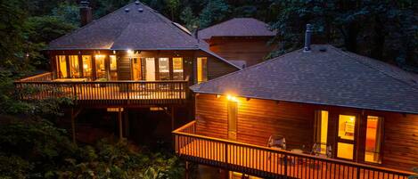 Two wooden cabins with balconies, surrounded by dense forest.