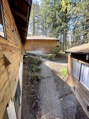 Una cabaña de madera con un camino de grava que lleva a un garaje.
