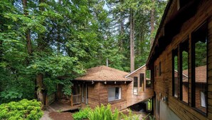 Una baita con facciata in legno, immersa in una fitta foresta. Dispone di un portico e una piccola terrazza.
