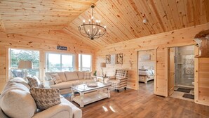 Ein gemütliches Blockhaus-Interieur mit einer Couch, einem Sessel und einem Esstisch.