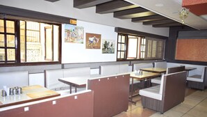 A restaurant with booth seating, wooden tables, and artwork on the walls. - Devis Grand (Puducherry)