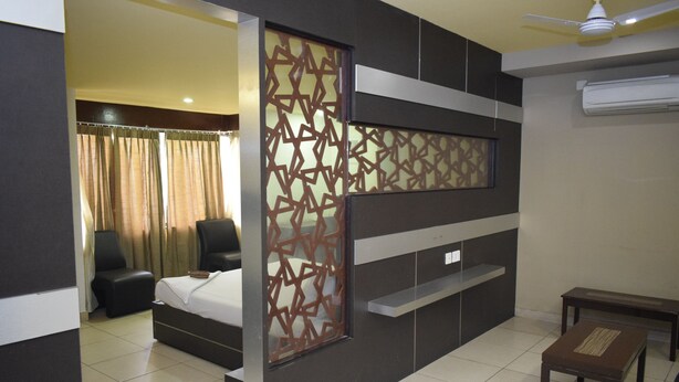 A modern hotel room with a bed, a desk, a chair, and a partition with geometric patterns. - Devis Grand (Puducherry)