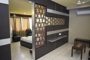 A modern hotel room with a bed, a desk, a chair, and a partition with geometric patterns. - Devis Grand (Puducherry)