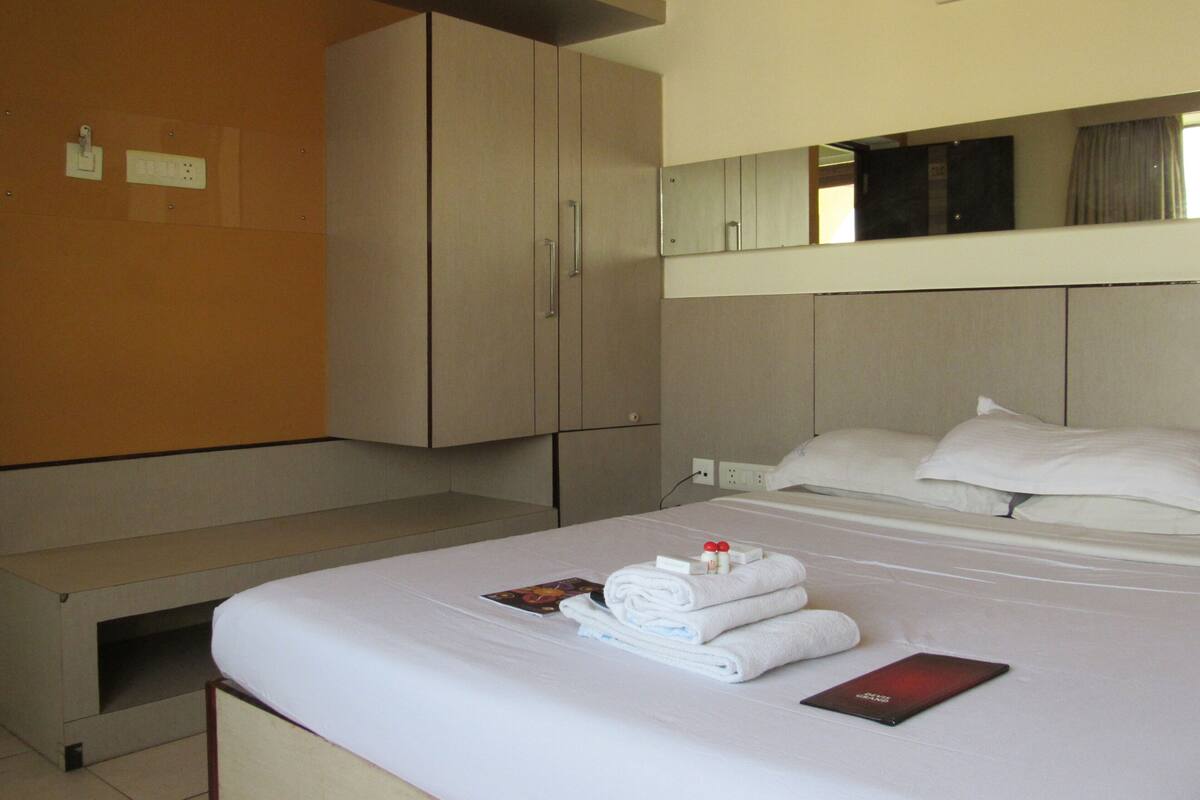 A hotel room with a bed, a bedside table, a wardrobe, and a mirror.