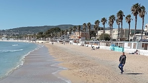 A beach with palm trees and buildings in the background. - Le Colibri dans la colline rated 3*. (La Ciotat)