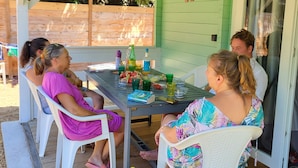 A covered patio with a table set for four people, surrounded by white chairs. - Le Colibri dans la colline rated 3*. (La Ciotat)