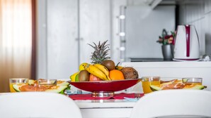 A kitchen with a fruit bowl on the counter, a kettle, and a table with glasses and a plate. - 1.1 Beautiful seafront with balcony and WIFI (Arona)