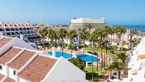 Un resort con varias edificaciones blancas, una piscina grande y palmeras.