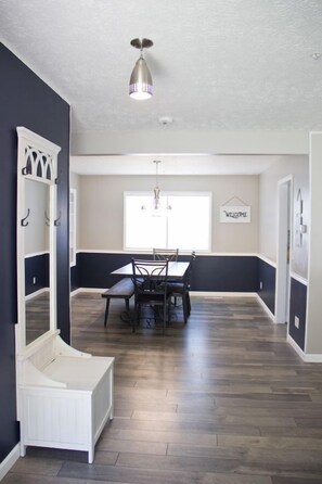 A dining area with a dark-colored bench, a white bench, and a dining table with chairs.