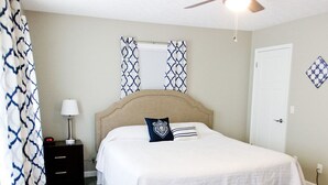A bedroom with a bed, a nightstand, a lamp, and patterned curtains.