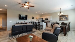 A spacious living room with a sofa, coffee table, and a dining area with chairs and a table. - The Plush (Branson West)