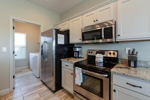 A kitchen with stainless steel appliances, white cabinets, and a granite countertop. - The Plush (Branson West)