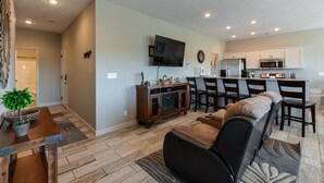 A modern living room with a sofa, dining table, and kitchen area. - The Plush (Branson West)