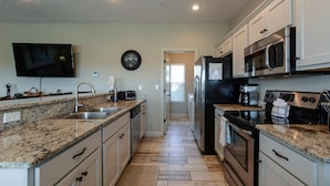 A kitchen with granite countertops, stainless steel appliances, and a tiled floor. - The Plush (Branson West)