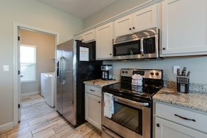A kitchen with stainless steel appliances, white cabinets, and a granite countertop.