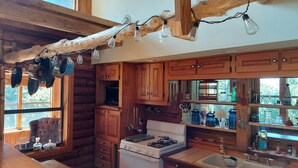 A rustic kitchen with wooden cabinets, a stove, and hanging light bulbs. - Hunters Hike (Yellville)