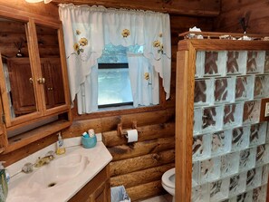 Een rustieke houten badkamer met een houten wastafel, toilet en een kastje met spiegel.