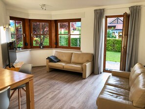 Relax in this serene living room with a comfortable sofa, garden views, and a flat-screen TV.