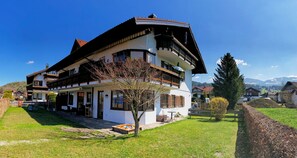 Enjoy a scenic view from the upper balcony of this charming chalet-style building, surrounded by a well-maintained lawn and garden.