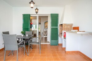 A dining area with wicker chairs, a table, and a small potted plant.