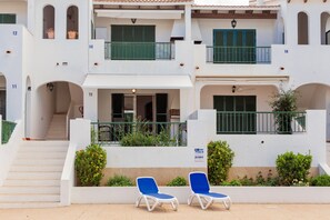 A building with numbered balconies, a staircase, and two lounge chairs. - Apartment Pregonda 13 Menorca with Wi-Fi, Pool, Terraces & Garden (Son Parc)