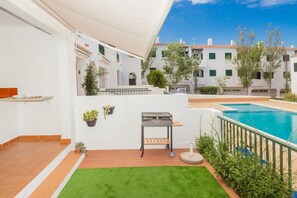 A patio with a pool, a grill, and a view of white buildings. - Apartment Pregonda 13 Menorca with Wi-Fi, Pool, Terraces & Garden (Son Parc)