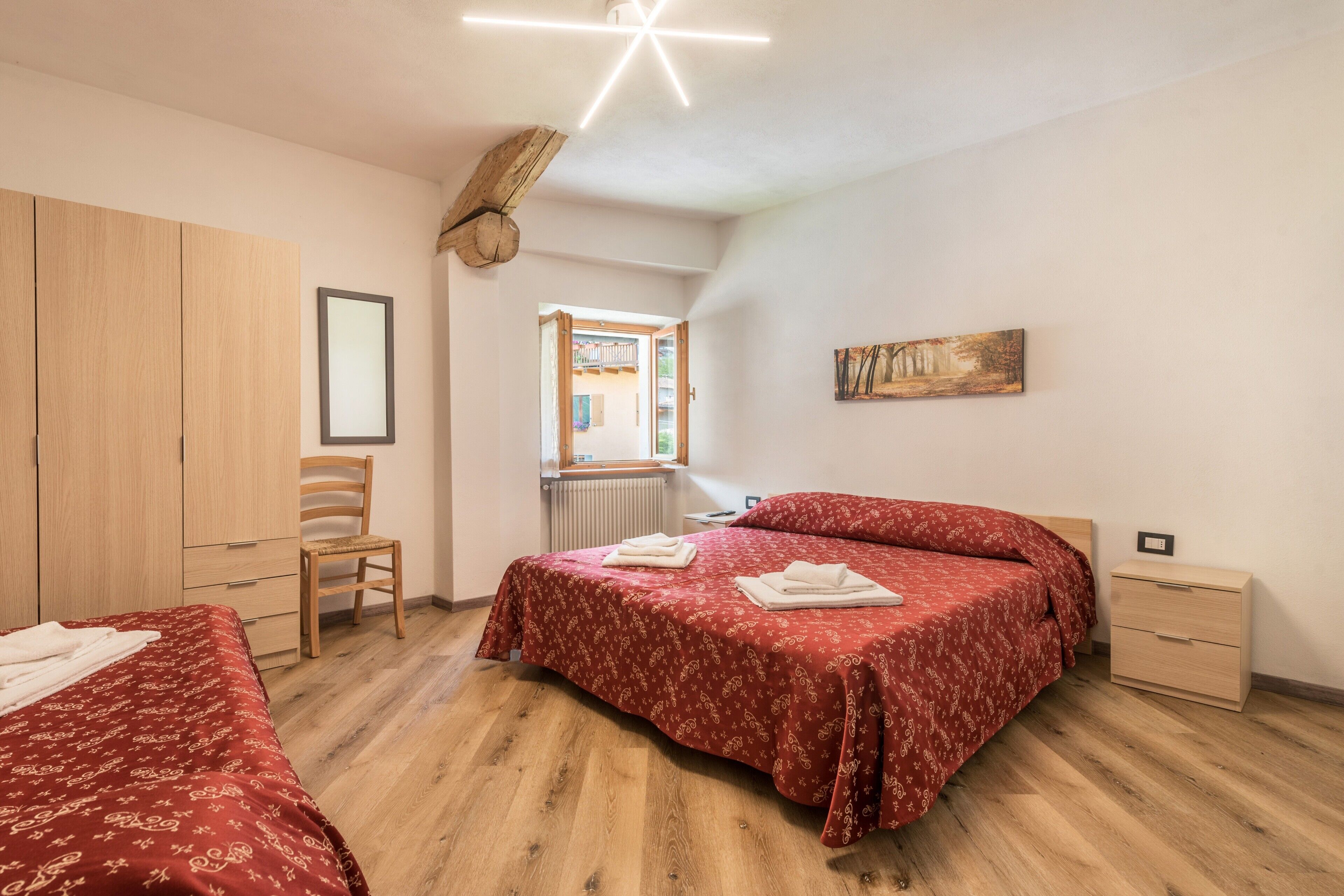 A bedroom with a bed, a chair, a wardrobe, a radiator, and a painting on the wall.