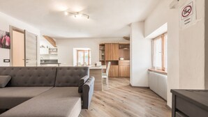 Una sala de estar moderna con un sofá, una zona de comedor y una cocina con armarios de madera.
