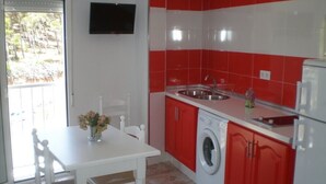A kitchen with red and white tiles, a washing machine, a sink, and a table with chairs.
