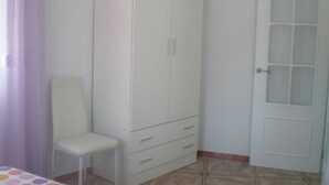 A room with a white wardrobe, a chair, and a door.