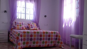 A bedroom with a bed, curtains, a chair, and a dresser.