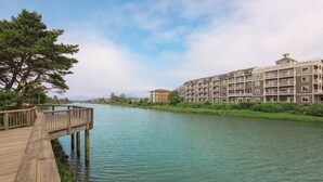 Un paseo a orillas del río que lleva a un hotel de varios pisos con balcones.